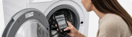 Frau scannt das Typenschild einer Waschmaschine mit ihrem Smartphone